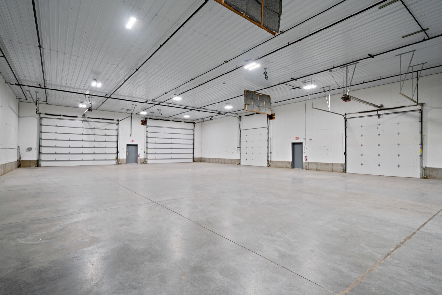 Interior of an industrial building with four overhead doors and a polished concrete floor.